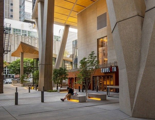 Pickard Chilton - дом на ножках в СиэтлеВ 2020 году в Сиэтле (США) построено многофункциональное здание "на ножках" Pickard Chilton по проекту архитектурной студии 2+U. Здание высотой 160 метров состоит из двух блоков: 19-этажного подиума и 38-этажной высотной части. При этом основная часть здания начинается с отметки 25 метров и опирается на ряд V-образных пилонов, что напоминает конструктивистские решения московских и ленинградских зданий на ножках ("Дом Авиаторов" в Москве, дома на Новосмоленской набережной в СПб и другие).Такое решение обусловлено несколькими причинами. Строительство в мегаполисах связано с жесткими ограничениями пятна застройки. Разрешение на строительство в обязательном порядке дополняется требованиями к благоустройству территории, которая фактически отсутствует. В проекте Pickard Chilton здание располагается на пересечении пешеходных потоков и велосипедных дорожек, которые архитекторы сохранили, подняв основную часть конструкций высоко над землей. Общая площадь свободного общественного пространства благодаря такому решению составила 2200 квадратных метров.Кроме этого, удалось сохранить историческое 4-этажное кирпичное здание 1890 года постройки, которое располагалось в зоне строительства небоскреба. В непосредственной близости расположены еще четыре малоэтажных здания, и нижняя часть небоскреба в уровне пилонов, выполнена в стилистике этих зданий.