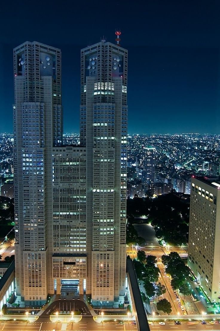 Комплекс зданий мэрии в ТокиоКомплекс зданий Токийской мэрии является визитной карточкой столицы Японии. Он спроектирован известным японским архитектором Кендзо Танге, одним из основоположников направления «метаболизма» в архитектуре. Ансамбль наглядно демонстрирует симбиоз модернизма и традиционного японского стремления к целостности и созерцательности. На воплощение в жизнь грандиозного проекта ушло более трех лет, строительство было окончено в 1991 году. На его возведение затрачено около 1 миллиарда долларов.Токийский муниципалитет состоит из трёх зданий, объединенных в единую архитектурную композицию: Токийское правительственное здание №1, Токийское правительственное здание №2 и Дом народного собрания. Высота первого, главного, здания почти 243 метра (45 этажей), также оно включает три подземных уровня. Второе — немного ниже (34 этажа и три поземных). Третье имеет всего восемь этажей, один из которых находится ниже уровня земли; оно расположено чуть поодаль от двух основных, напротив первого корпуса. Все три здания объединены между собой узкими «мостами». В центре образовавшегося квадрата расположена площадь в форме веера, вокруг разбит сквер.Главное здание напоминает футуристический готический собор — на высоте 33-го этажа оно раскалывается на две башни — Северную и Южную. Эти башни неофициально окрестили "японским Нотр-Дам де Пари". В наружном и внутреннем дизайне Токийского муниципалитета используются элементы, напоминающие компьютерные микросхемы. В частности, изображения микропроцессоров находятся на потолке второго этажа главного корпуса, а также в других частях здания.Здания возведены по технологиям сейсмостойкого строительства. Конструкция способна выдерживать 8-балльное землетрясение. Воздействие силы ветра удалось сократить на треть путём правильной ориентации здания в пространстве. Использование округлых форм с наветренной стороны и грубой текстуры с подветренной, расположение наклона крыш высотных башен под углом 45 градусов и наличие высоких деревьев в окрестности, позволило снизить ветровые нагрузки.